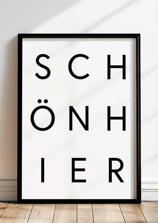 Typografieposter „SCHÖN HIER“ in Schwarz im schwarzen Holzrahmen, stehend auf dem Boden