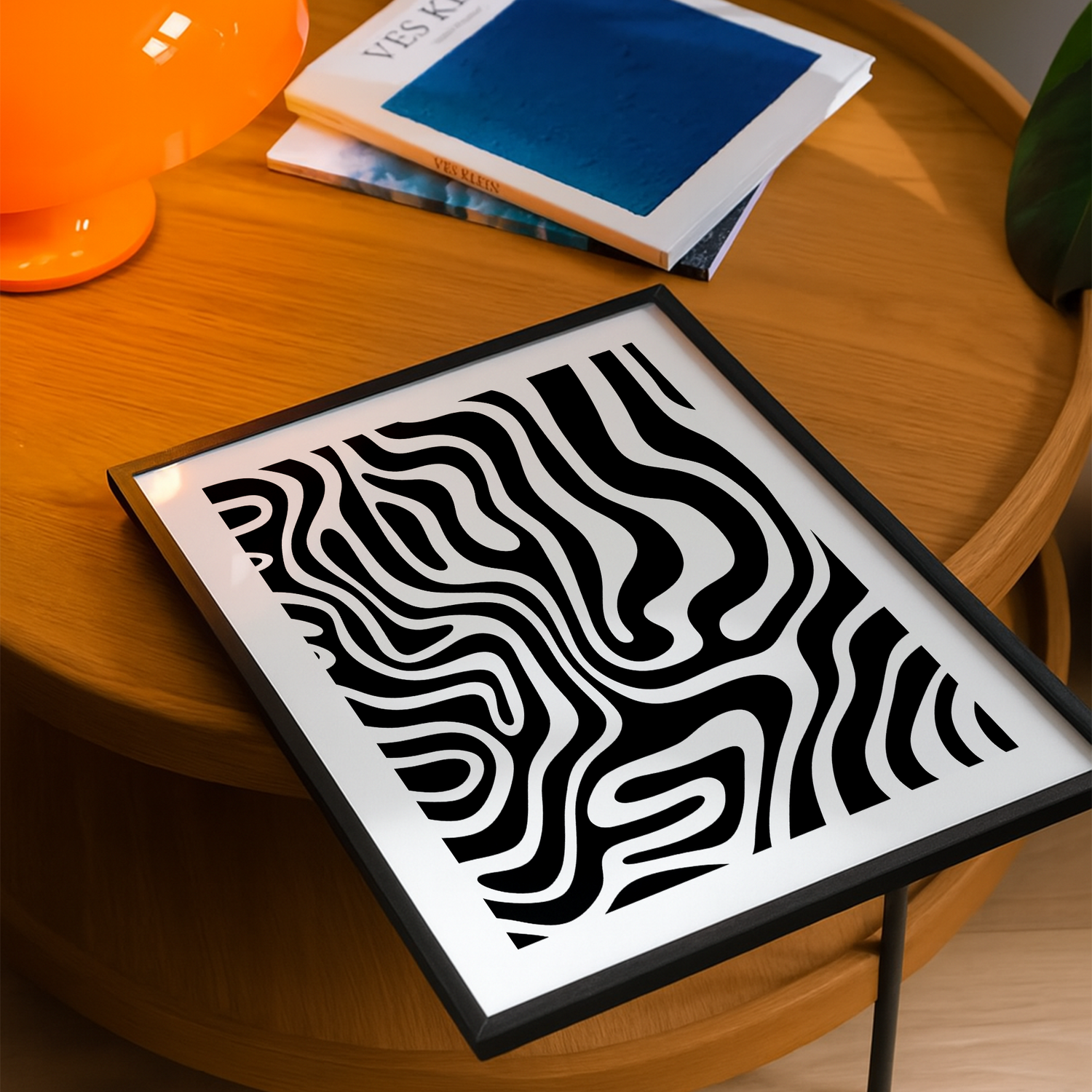 wohnzimmertisch mit einem abstrakten kunstdesign als poster in einem schwarzen rahmen