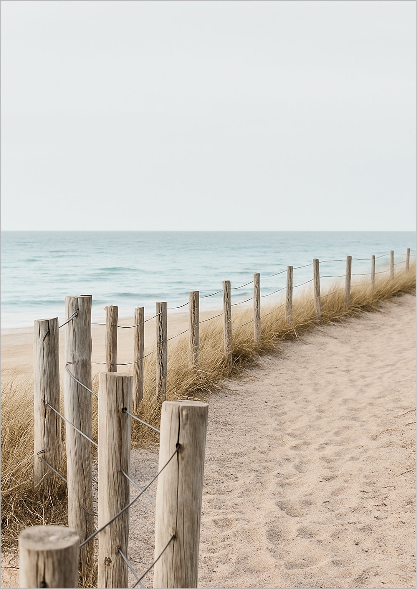 Holzpfosten mit Draht entlang eines Sandwegs am Meer, von Strandgras gesäumt