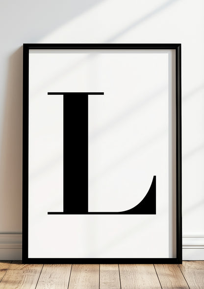 Poster Buchstabe „L“ in schwarzem Holzrahmen steht auf dem Boden