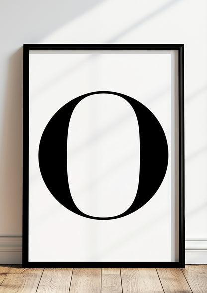 Poster Buchstabe „O“ in schwarzem Holzrahmen steht auf dem Boden