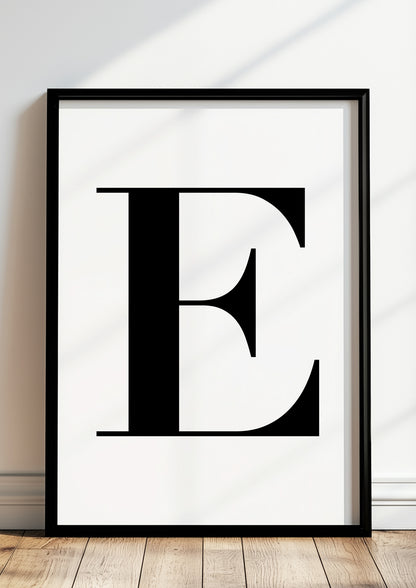 Poster Buchstabe „E“ in schwarzem Holzrahmen steht auf dem Boden