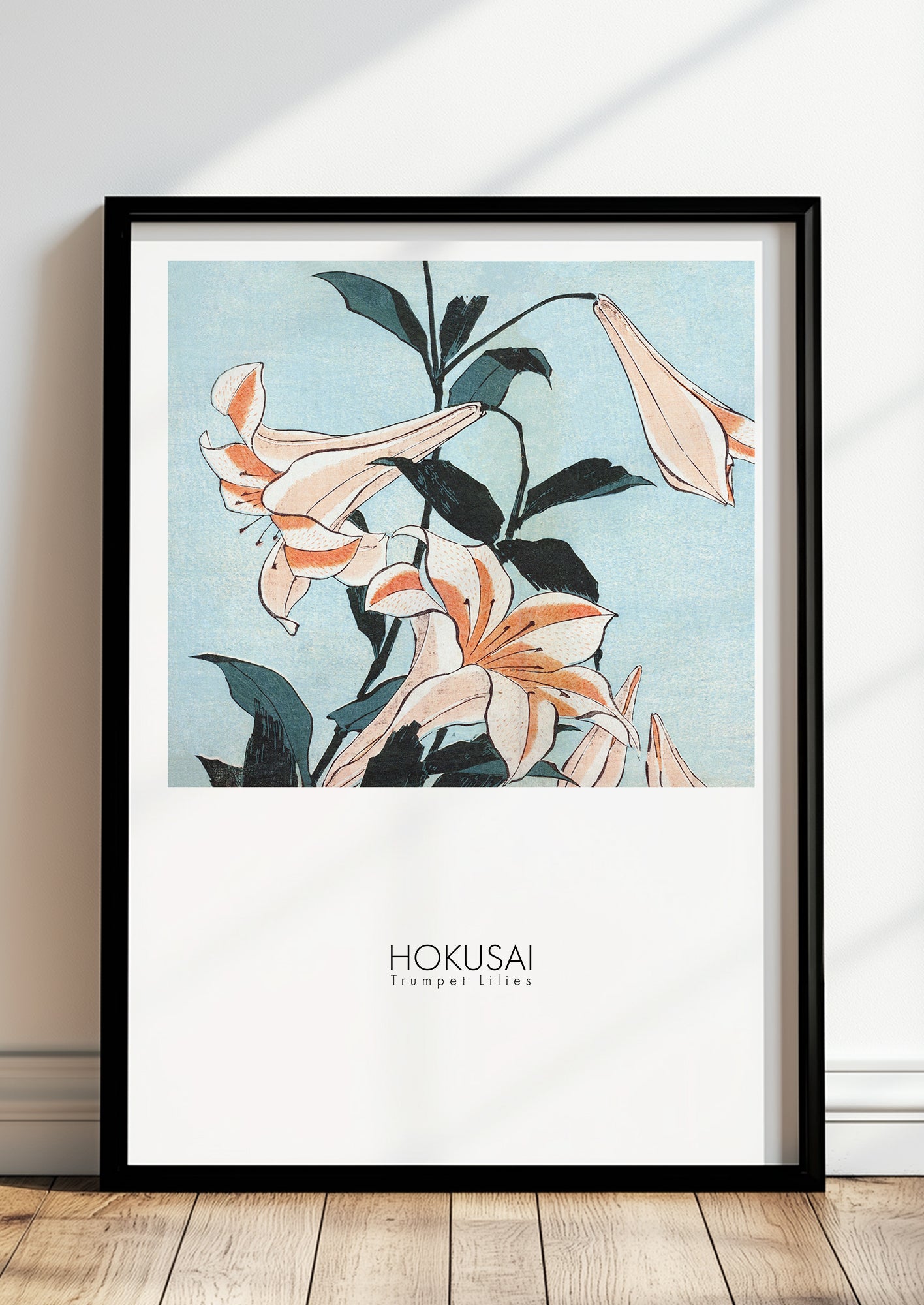 Trumpet Lilies von Hokusai als Poster, in schwarzem Rahmen, stehend auf dem Boden, angelehnt an einer Wand