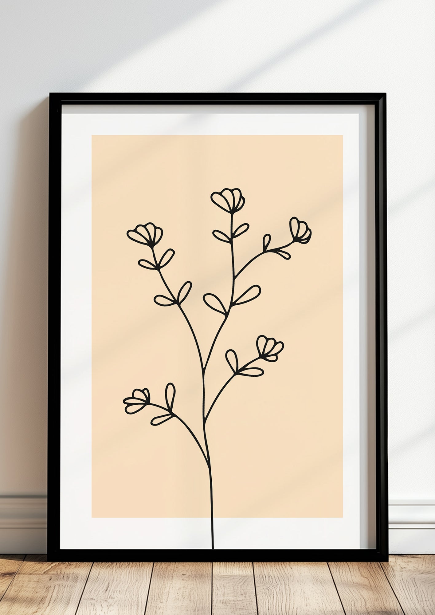 Poster „Line Art Blütenzweig“ in schwarzem Holzrahmen steht auf dem Boden