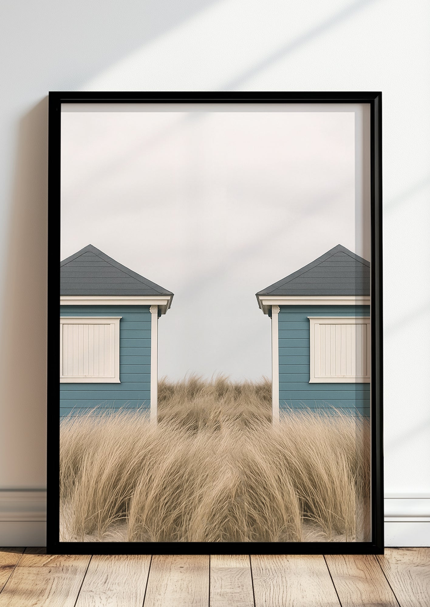 Fotoposter mit symmetrischen Strandhütten im schwarzen Rahmen vor heller Wand