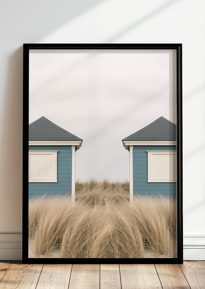 Fotoposter mit symmetrischen Strandhütten im schwarzen Rahmen vor heller Wand