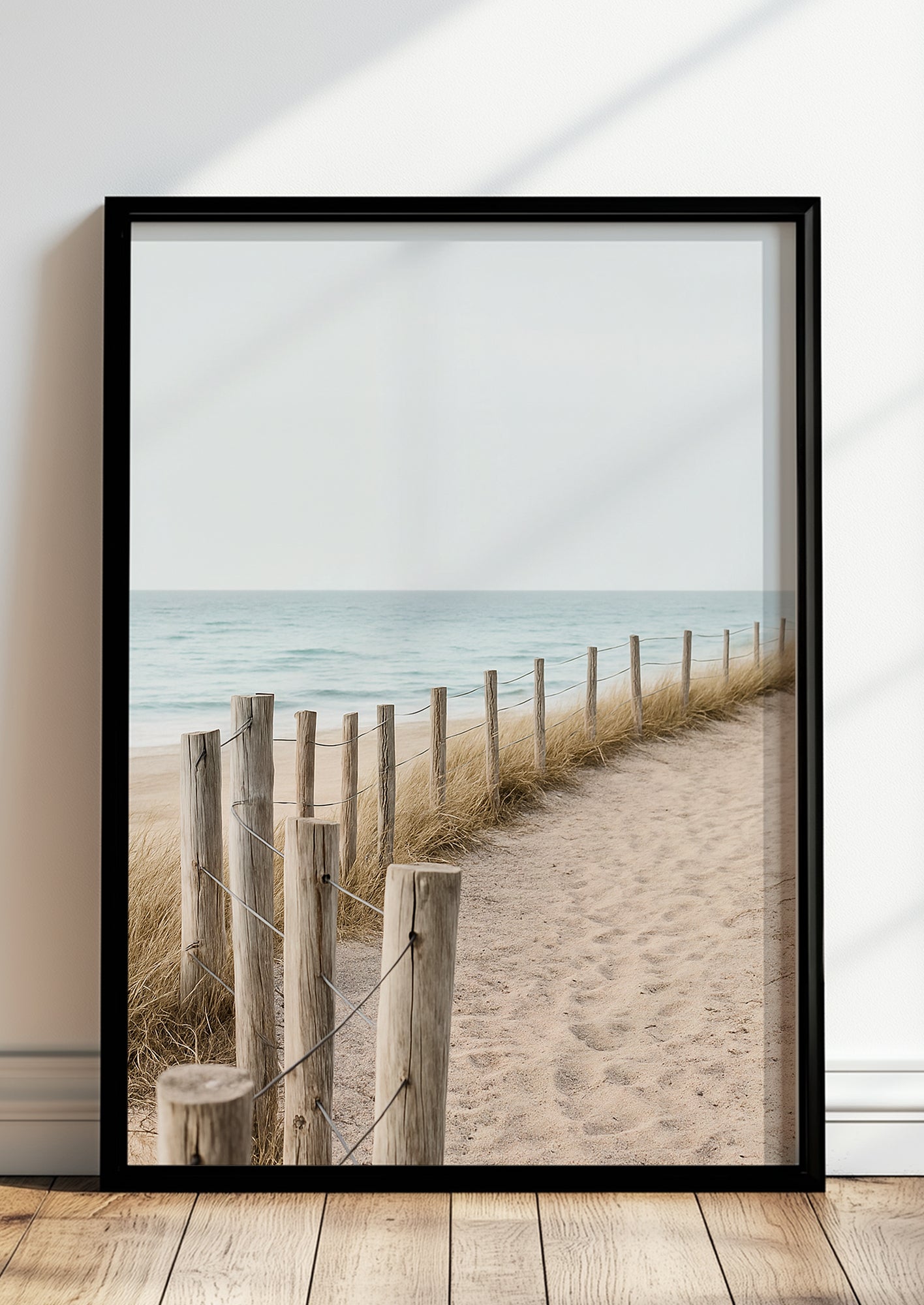 Fotoposter mit Dünenweg im schwarzen Rahmen vor heller Wand mit Naturakzenten