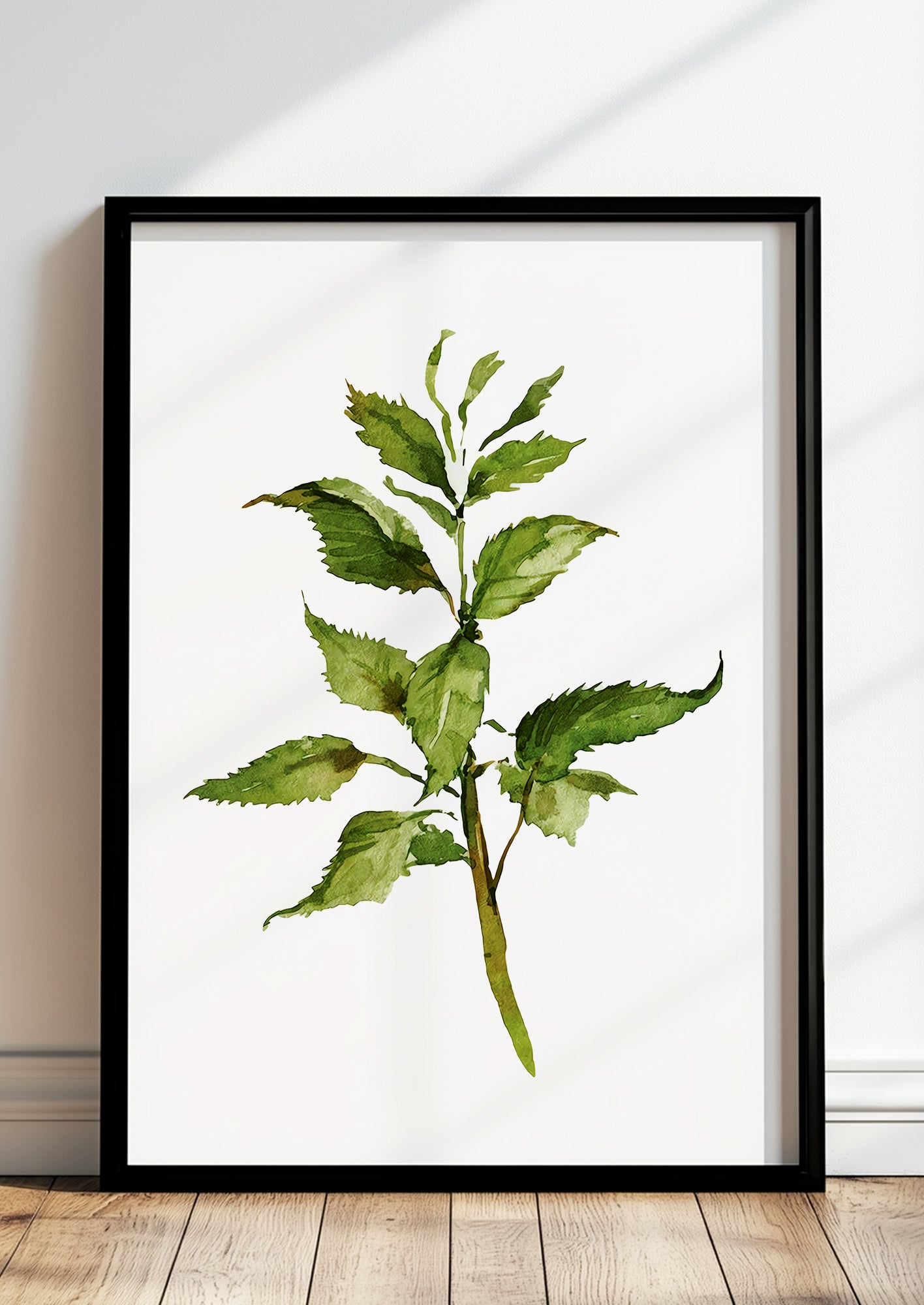 Gerahmtes Poster mit Aquarellzweig lehnt auf dem Boden vor einer hellen Wand
