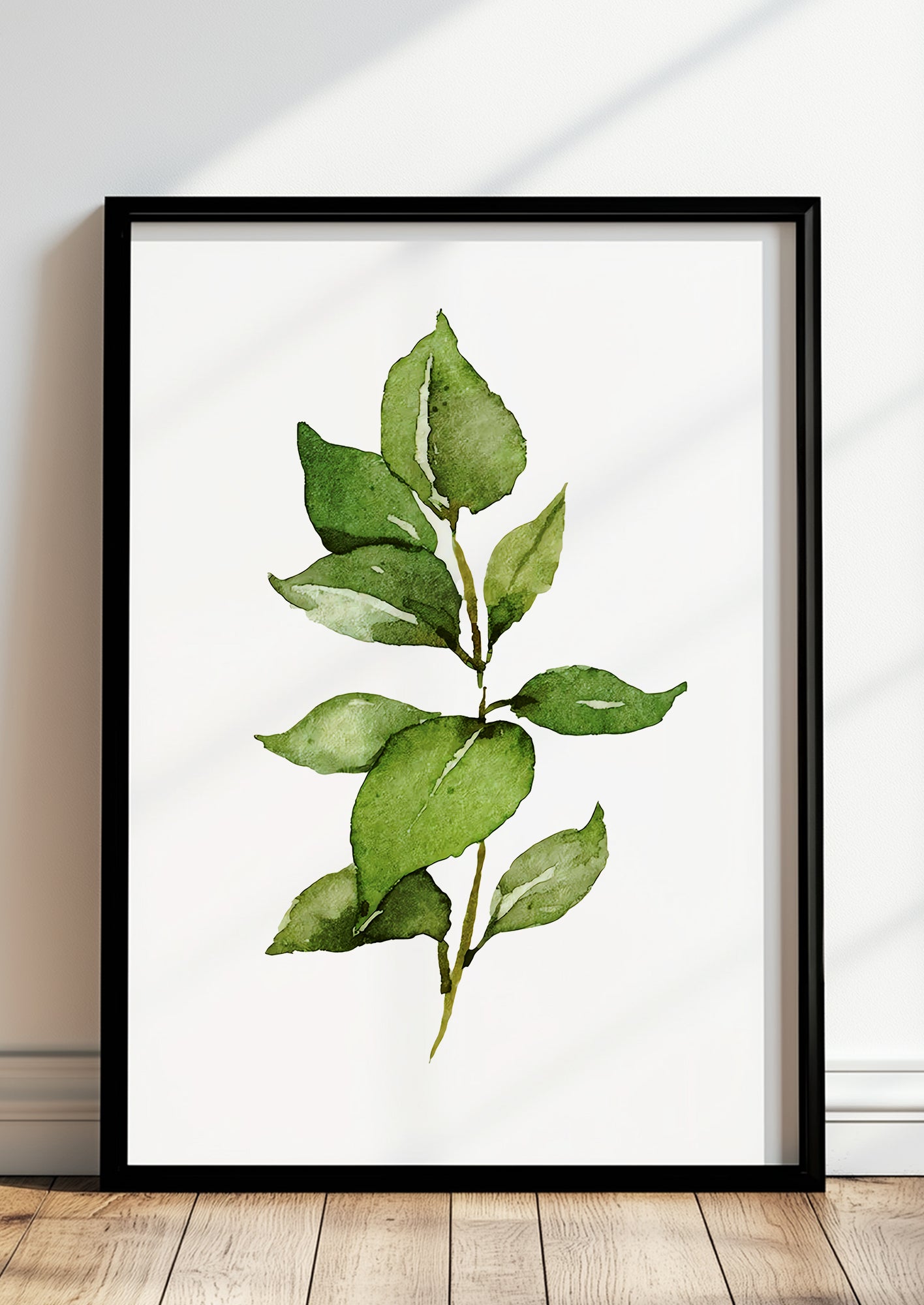 Gerahmtes Poster mit Aquarellzweig im Rahmen auf dem Boden vor einer hellen Wand