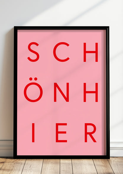 Typografieposter „SCHÖN HIER“ in roter Schrift im schwarzen Holzrahmen, stehend auf dem Boden