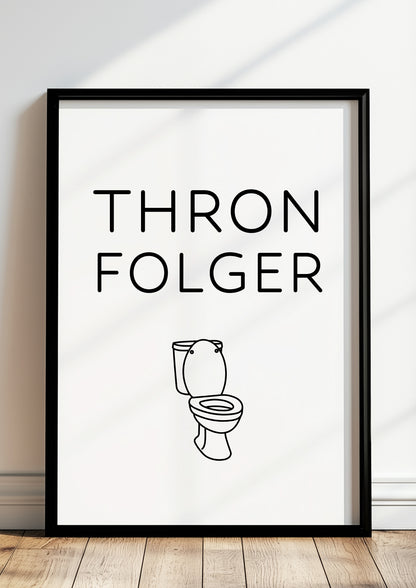 Witziges Wandbild mit Aufschrift ‚Thronfolger‘ und Toiletten-Grafik im schwarzen Rahmen, modernes Badezimmer-Poster im skandinavischen Design auf hellem Holzfußboden