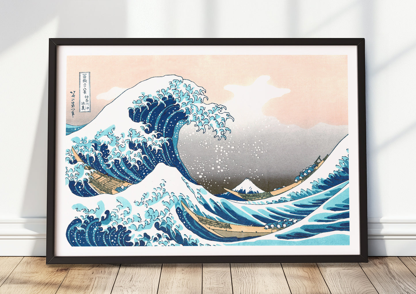 Katsushika Hokusai – The Great Wave off Kanagawa als Poster mit schwarzem Rahmen, stehend am Boden an eine Wand gelehnt
