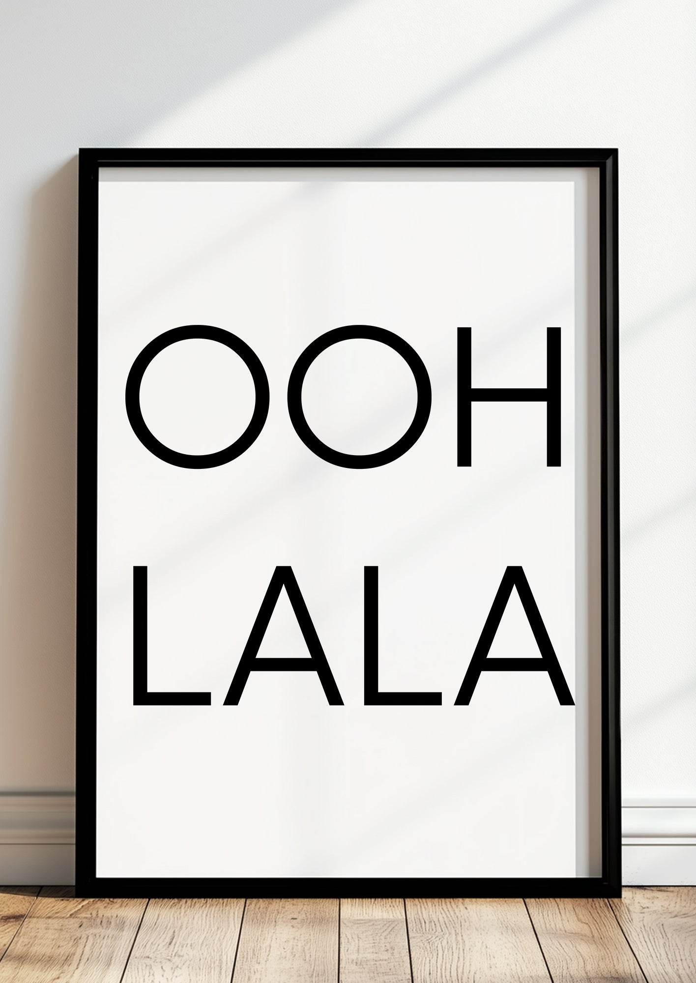 Gerahmtes Poster „OOH LA LA“ in schwarzem Rahmen, inszeniert in moderner Wohnumgebung.